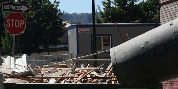 Construction debris in a dumpster near a stop sign and street signs.