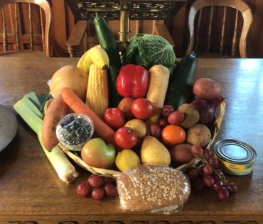 Basket of assorted fresh fruits and vegetables on a table.