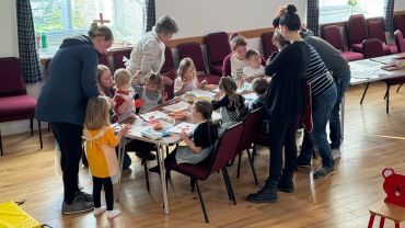 Children and adults doing crafts together at a table.