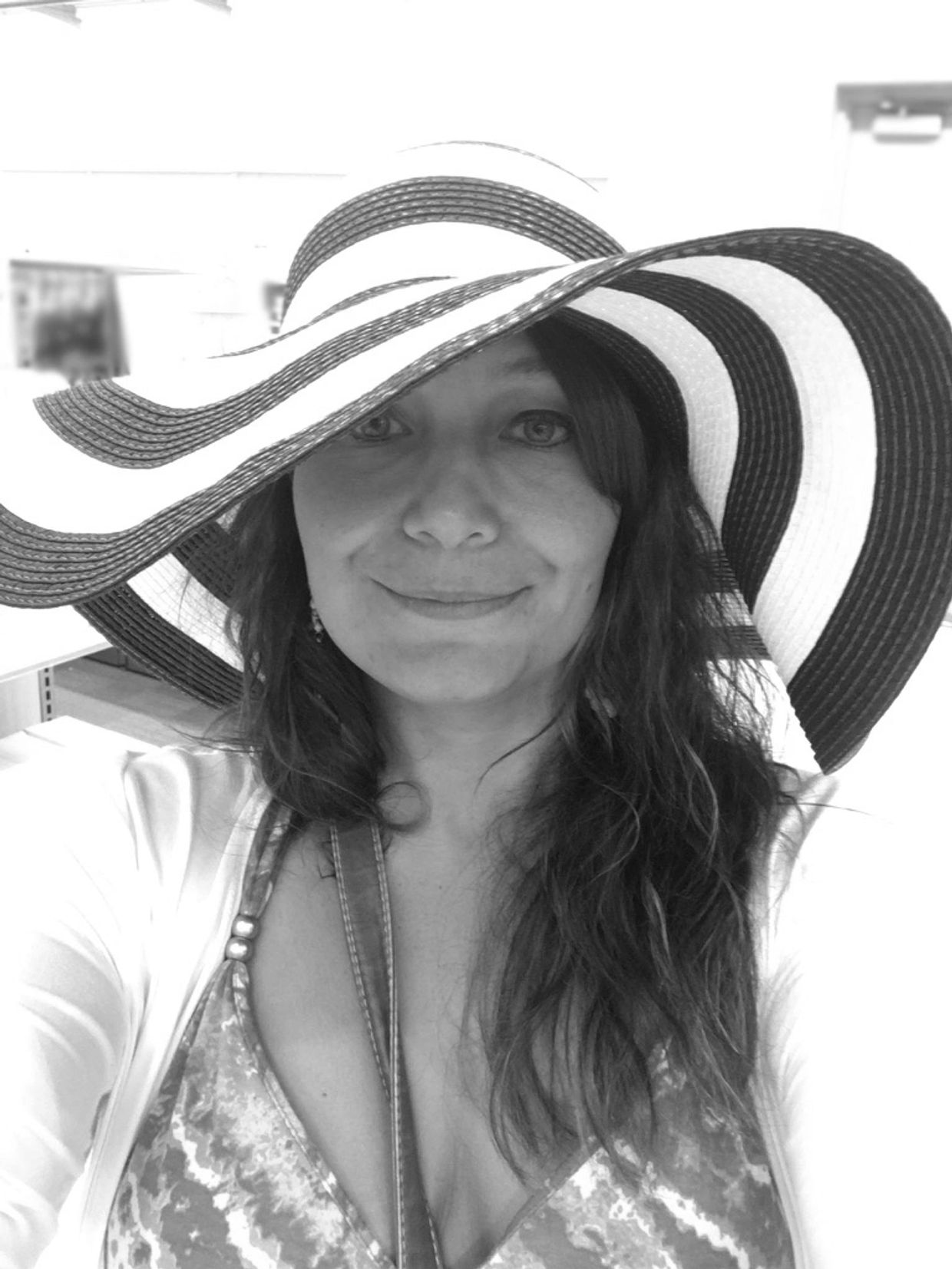 Woman with a wide-brimmed striped hat smiling.