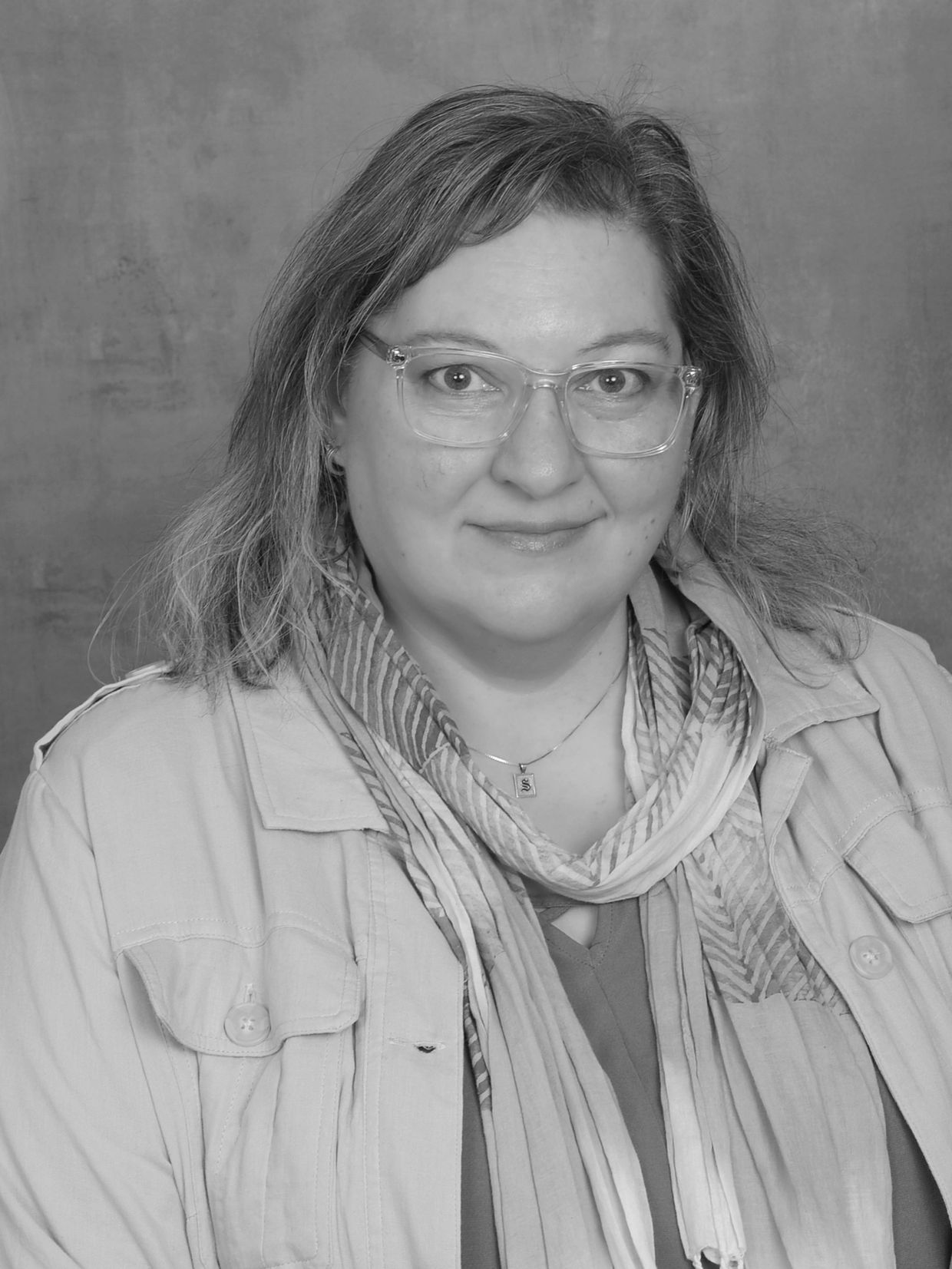 Smiling woman wearing glasses and a scarf.