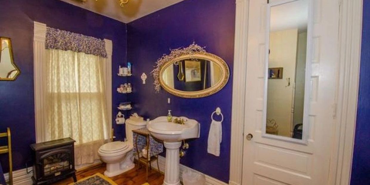 Toilet and pedestal sink in a spacious bathroom along with a clawfoot tub with shower.