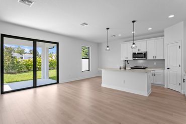 Bright modern kitchen with island and sliding glass doors to backyard.