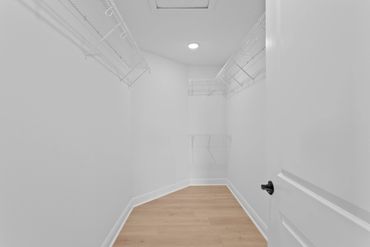 Empty walk-in closet with white wire shelving and wood floor.