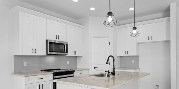 Modern white kitchen with marble countertop island and black fixtures.