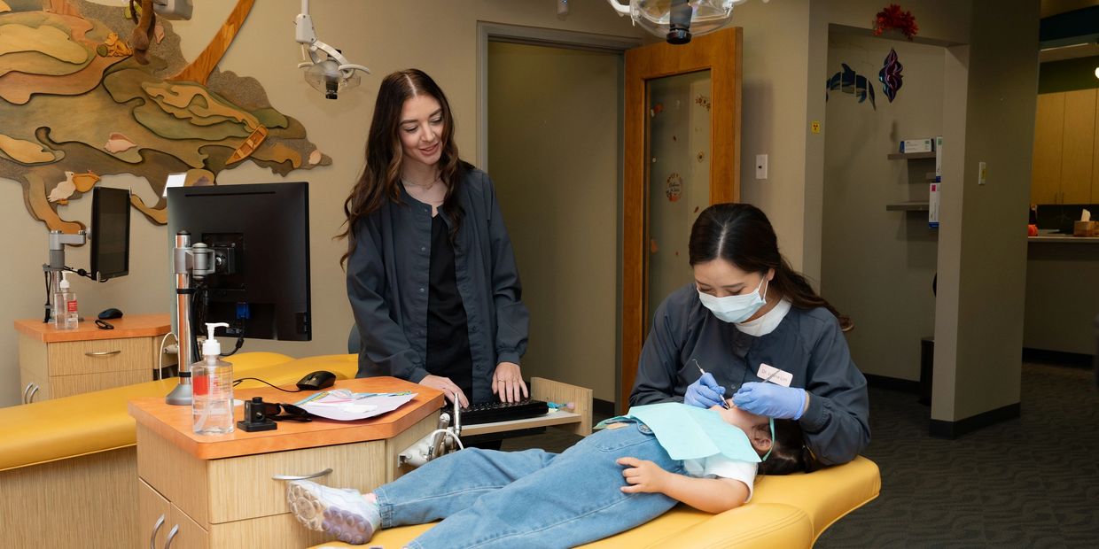 dental professional performs an examination on a young child lying down