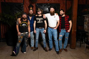 Group of five men wearing casual western-style clothing posing together.