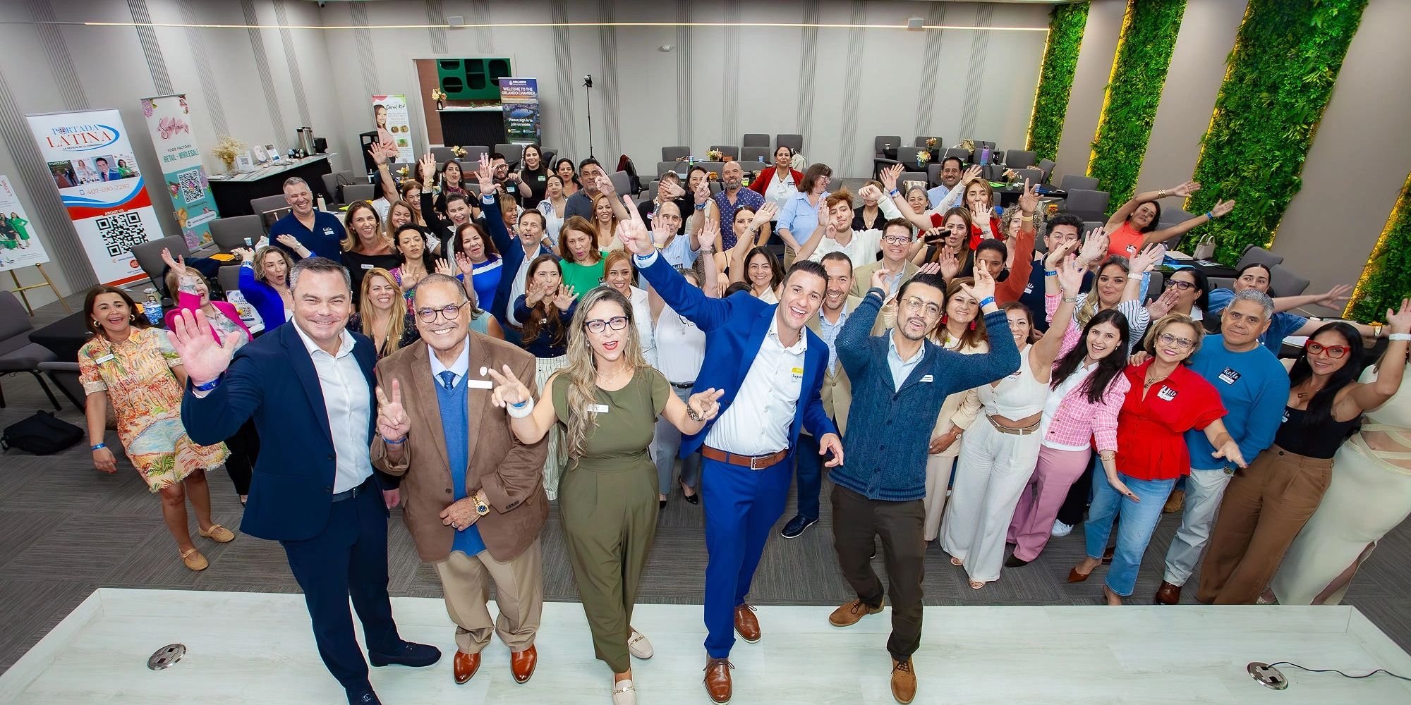 Large group of happy people waving at the camera indoors.