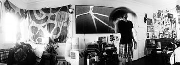 Man in a cluttered room holding a hat.
