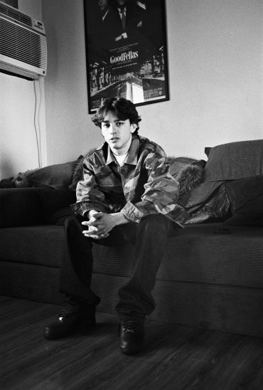 Young man sitting on a sofa in a black-and-white photo.