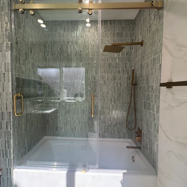 Modern bathroom with glass shower doors and brass fixtures.