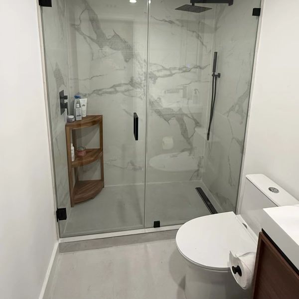 Modern bathroom with glass shower enclosure and marble walls.