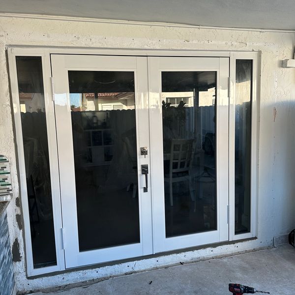 White double glass doors with side panels in a home exterior.