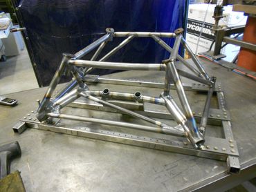 Metal frame structure under construction on a workbench.