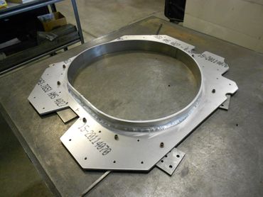 A large metal circular frame with markings on a workbench.