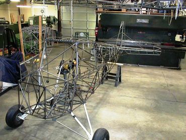 Metal frame structure of a small aircraft under construction in a workshop.