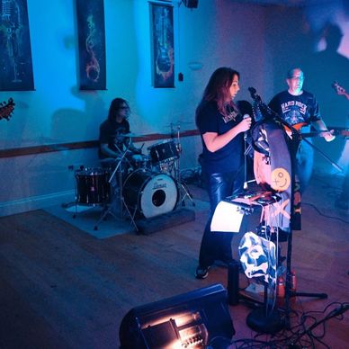Band performing live in a dimly lit room with blue and purple lighting.