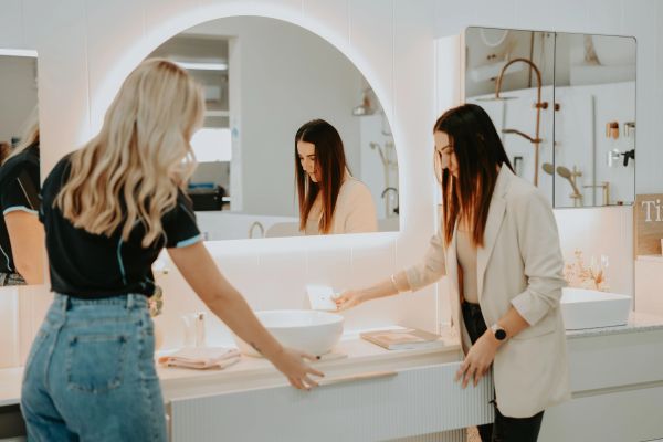 Two women looking at a bathroom sink in a modern setting.