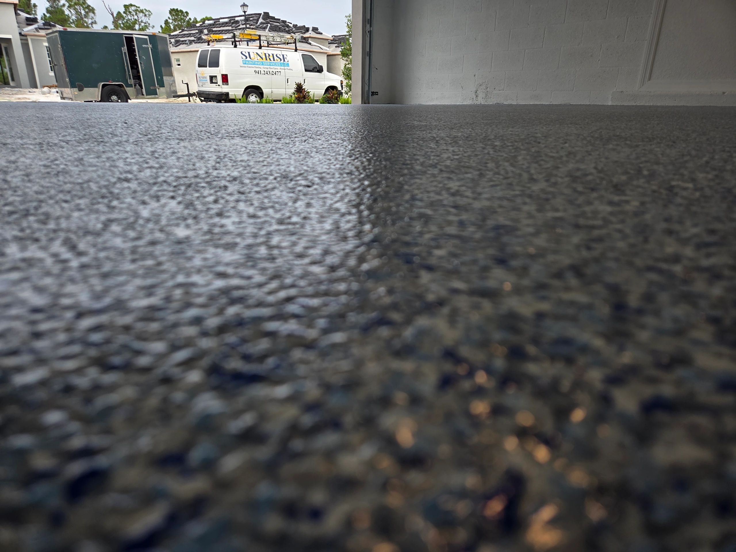 Freshly coated garage floor with two service vehicles outside.