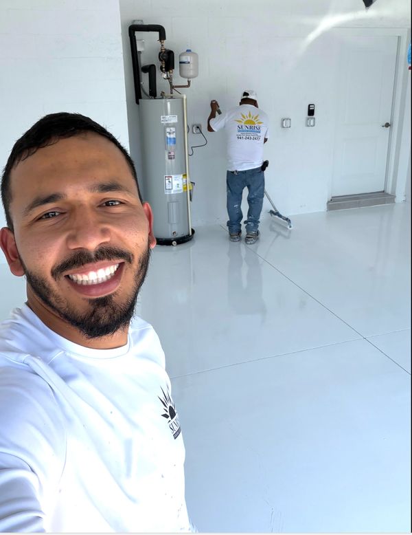 Two men in white shirts working in a clean room with a water heater.