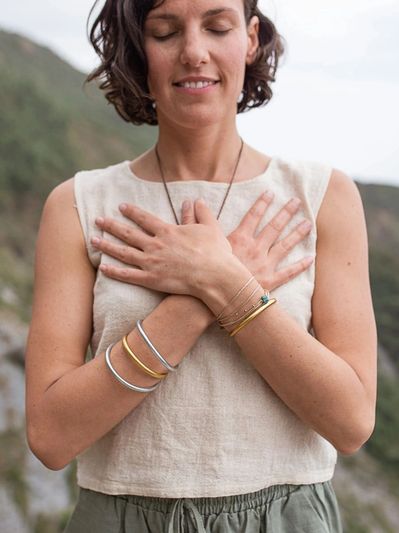 Femme méditant en plein air, les mains croisées sur la poitrine.