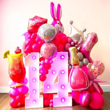 Colorful pink-themed 14th birthday balloon arrangement with large number lights.