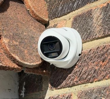 White security camera mounted on a brick wall.