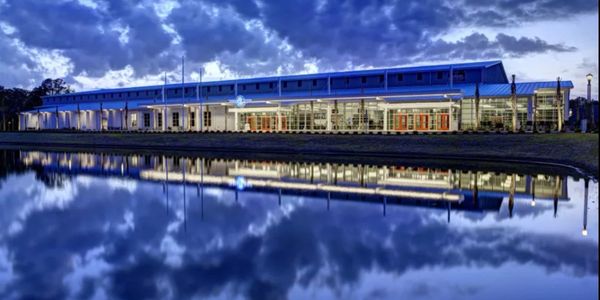 Modern building reflected in calm water under a dramatic evening sky.