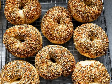 Freshly baked everything bagels on a cooling rack.