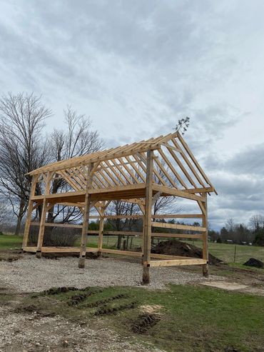 Wooden barn frame under construction in a field.