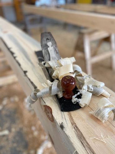 Wood plane with wood shavings on a carved piece of wood.