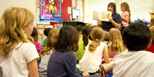 Teacher reading Lacinda the Lion to a group of children in a school setting