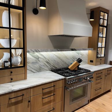 Modern kitchen with wooden cabinets and marble countertops.