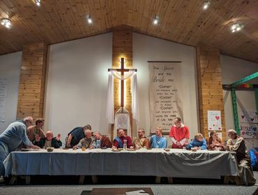 A group reenacting The Last Supper inside a church with a wooden cross in the background.