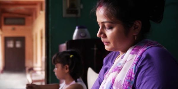 Indian woman and child engaged in activity indoors.