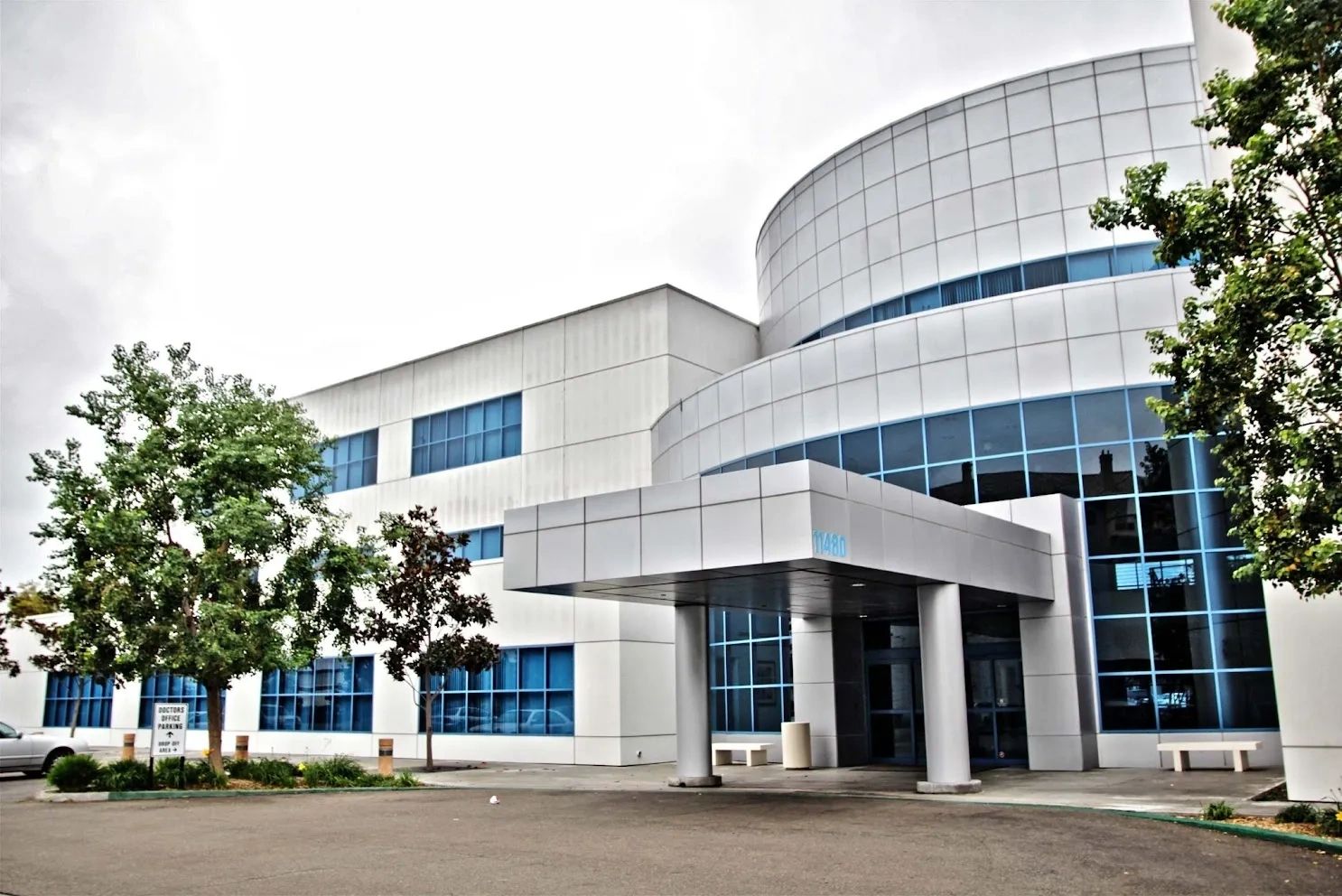 A modern, multi-story office building with a curved, glass-paneled facade and a covered entrance.