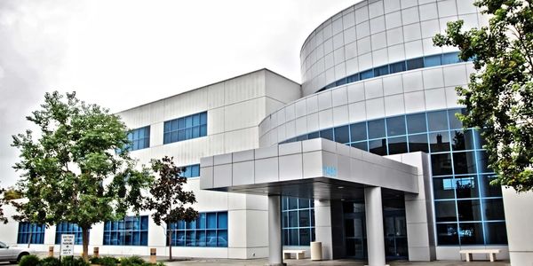 A modern, multi-story office building with a curved, glass-paneled facade and a covered entrance.