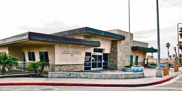 A stone and stucco building, the Vincent G. Moorhouse Lifeguard Headquarters, with a ramp