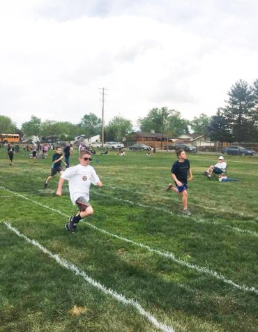 Kids running a race on a grassy field.