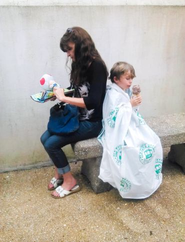 Woman and boy sitting back to back, boy eating ice cream.