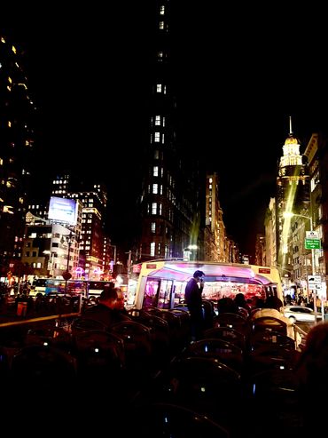 Night view of a city street with illuminated buildings and a bus.
