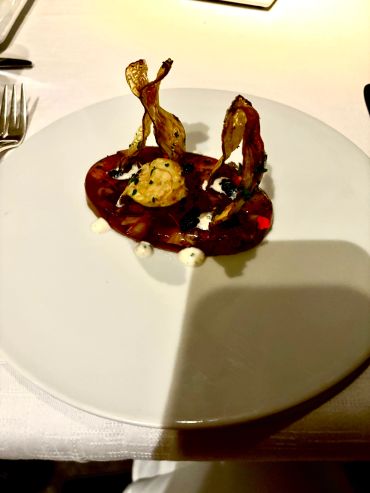 Artistic gourmet dish with crispy elements and creamy sauce.