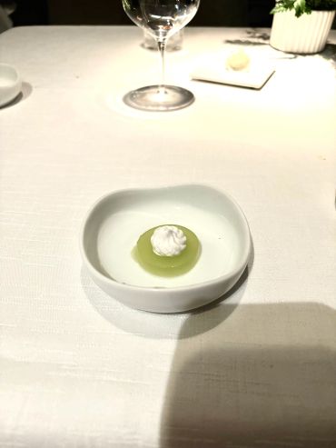 Small green dessert with cream on white dish.