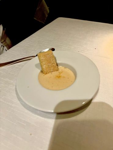 A cracker dipped in a creamy sauce on a white plate.