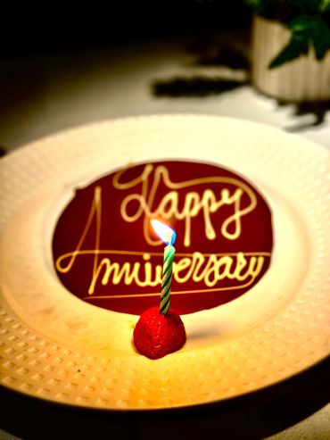 Anniversary candle on a strawberry with chocolate plate.