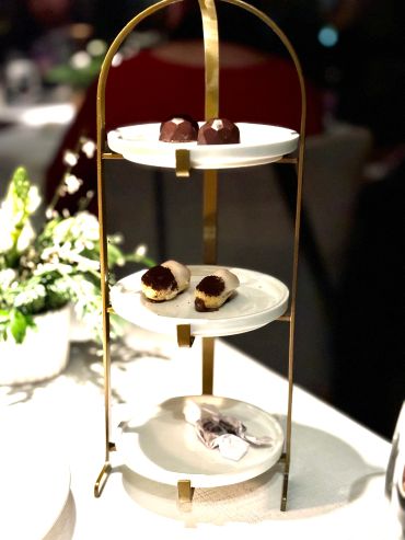 Three-tiered dessert stand with chocolates and pastries.