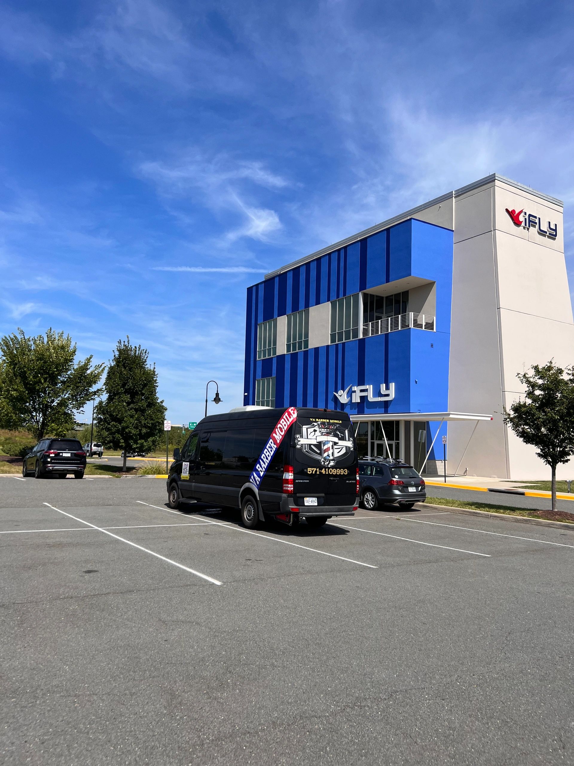 iFLY indoor skydiving building with a black VA Barber Mobile van in the parking lot.