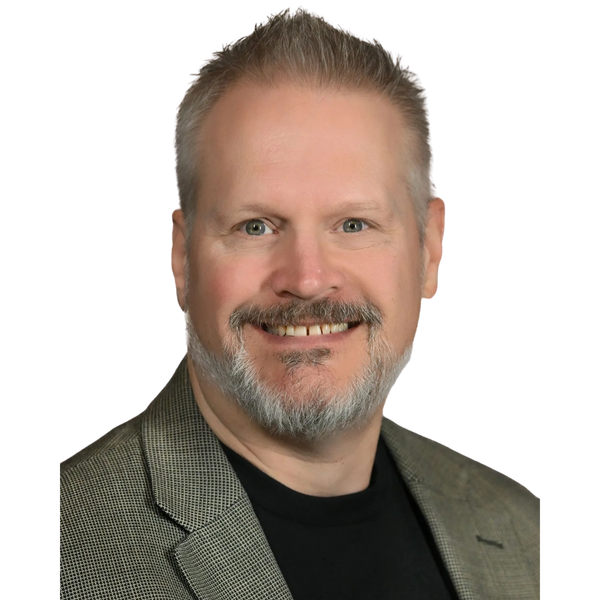 Smiling man with a gray beard wearing a checkered blazer and black shirt. Daran Adiar