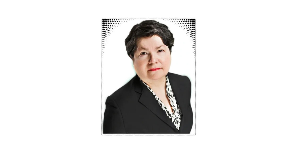 Professional headshot of a woman in a black blazer with a patterned blouse.