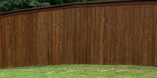 Brown wooden fence with green grass in front.